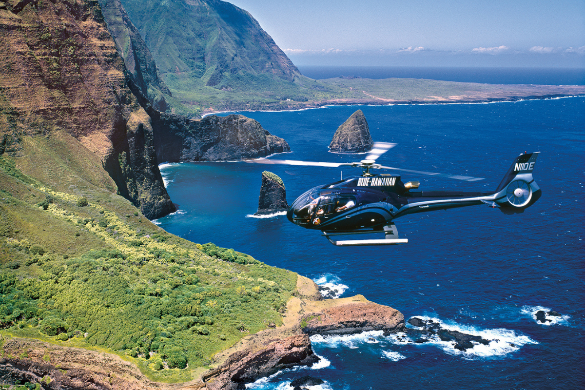 Blue Hawaiian helicopter flying along Maui’s rugged Na Pali coastline over ocean cliffs – top things to do in Maui.